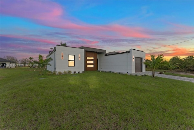 contemporary house with an attached garage, concrete driveway, and a yard