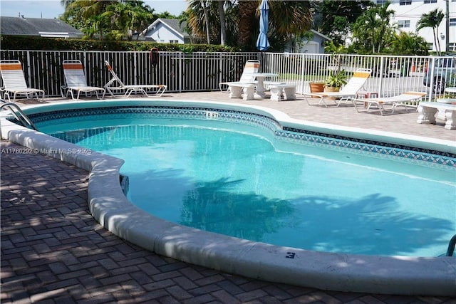 community pool with a patio area and fence