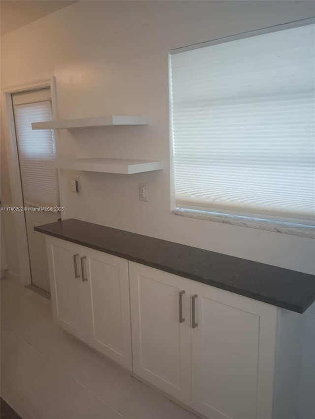 interior space with open shelves, dark countertops, and white cabinetry