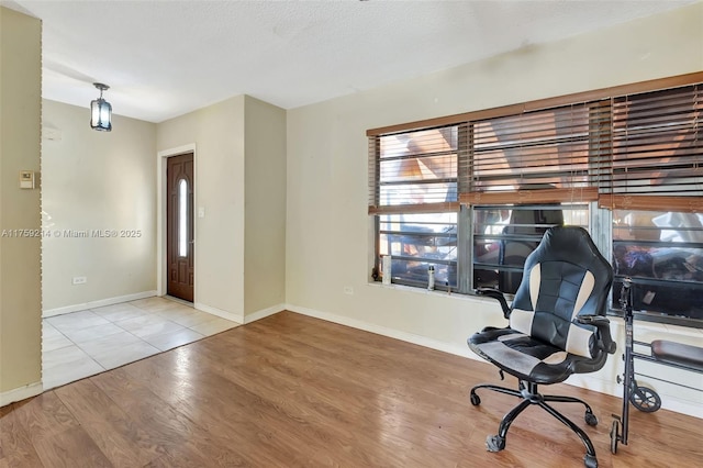 unfurnished office with a textured ceiling, baseboards, and wood finished floors