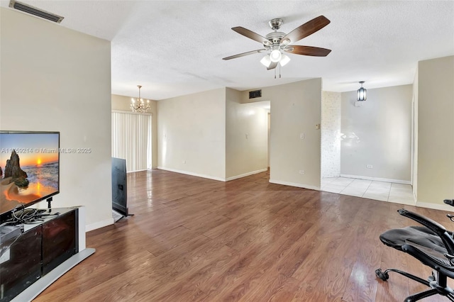 living room with visible vents, ceiling fan with notable chandelier, a textured ceiling, and wood finished floors