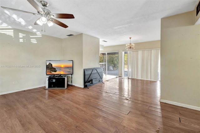 living area featuring ceiling fan with notable chandelier, wood finished floors, and baseboards