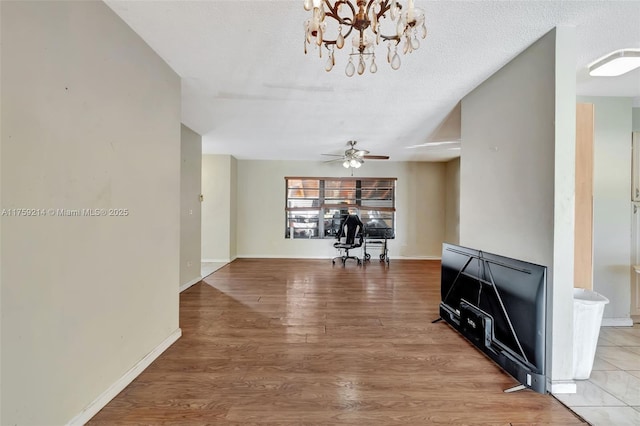 interior space with baseboards, a textured ceiling, and wood finished floors