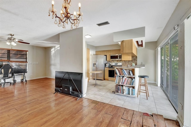 dining space with visible vents, baseboards, light wood-style floors, and a textured ceiling