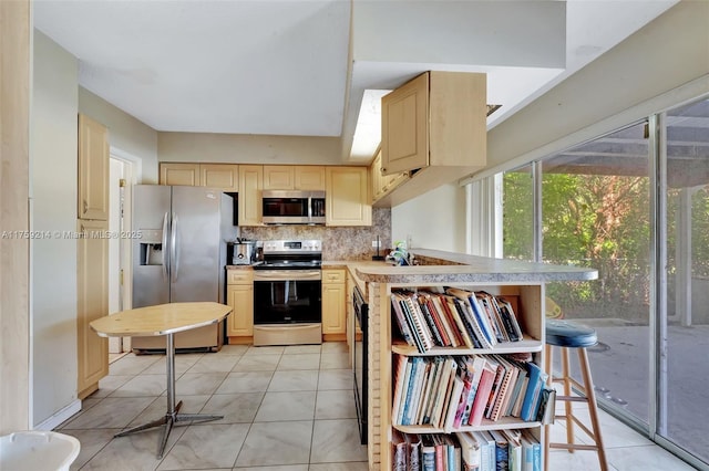 kitchen with backsplash, light brown cabinets, light countertops, light tile patterned floors, and stainless steel appliances