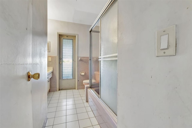 full bathroom with tile walls, a wainscoted wall, toilet, tile patterned floors, and vanity