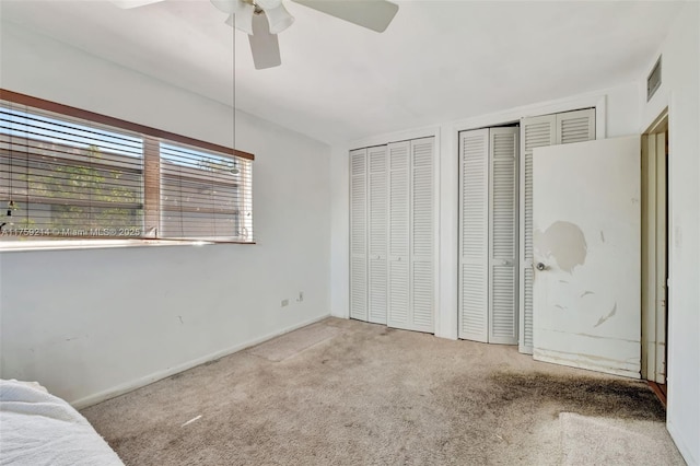 unfurnished bedroom with visible vents, ceiling fan, baseboards, multiple closets, and carpet floors