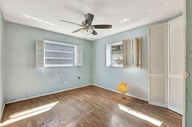 unfurnished bedroom featuring a closet, ceiling fan, baseboards, and wood finished floors