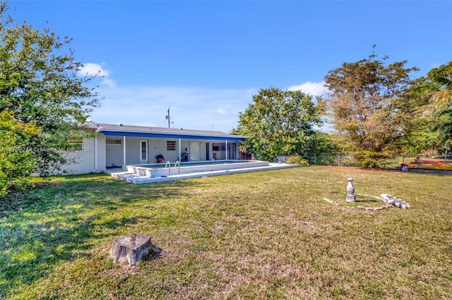 rear view of house with a yard, fence private yard, and an outdoor pool