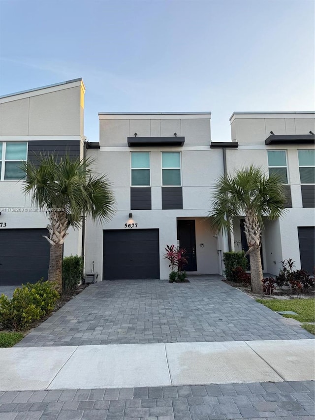 view of front of home with stucco siding, decorative driveway, and a garage