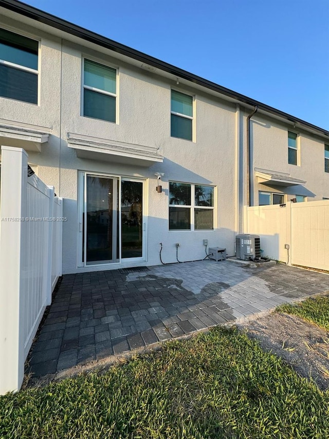 back of house with stucco siding, cooling unit, a patio, and fence