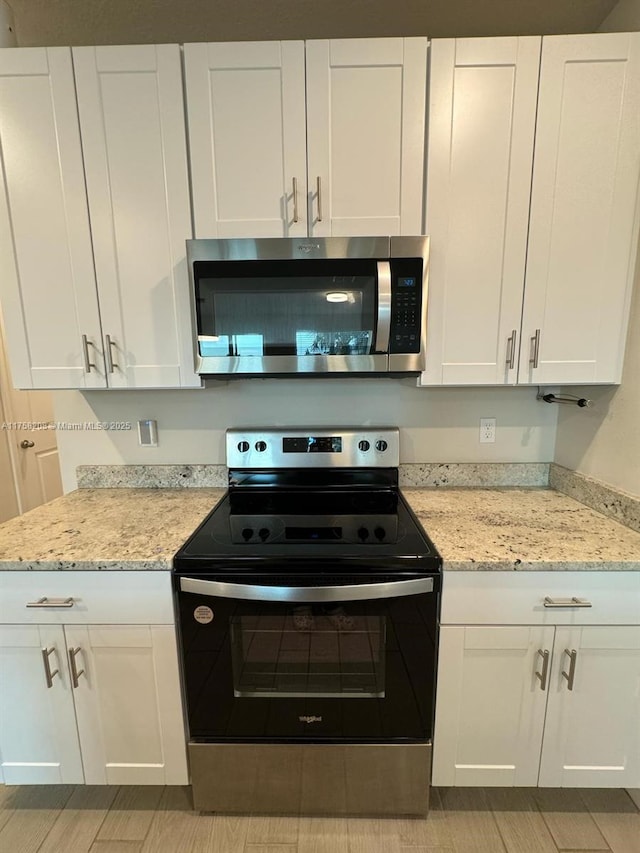 kitchen with white cabinetry, light stone counters, and stainless steel appliances