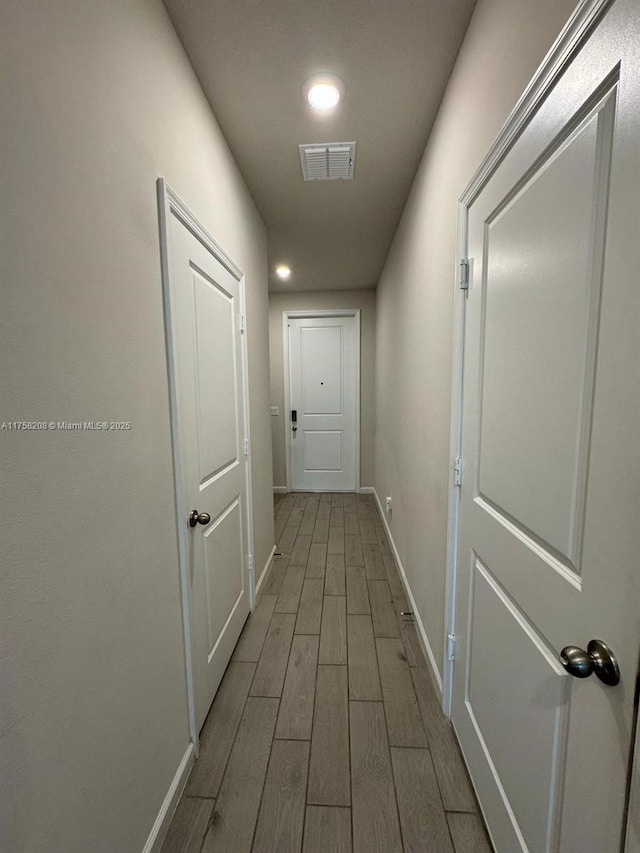 corridor with baseboards, visible vents, and wood finish floors