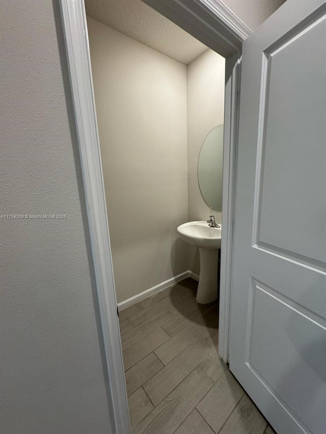 bathroom featuring a sink, baseboards, and wood finished floors