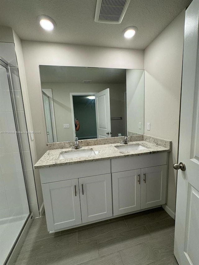 full bath featuring double vanity, visible vents, a shower stall, and a sink