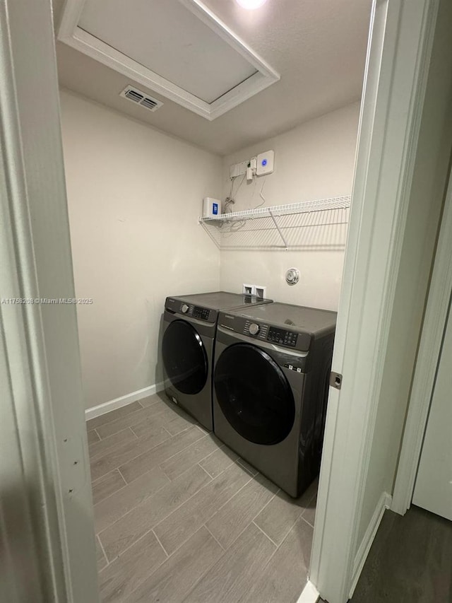 clothes washing area with visible vents, wood tiled floor, laundry area, attic access, and washer and clothes dryer