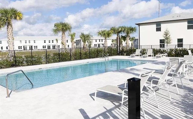 community pool with a patio area and fence