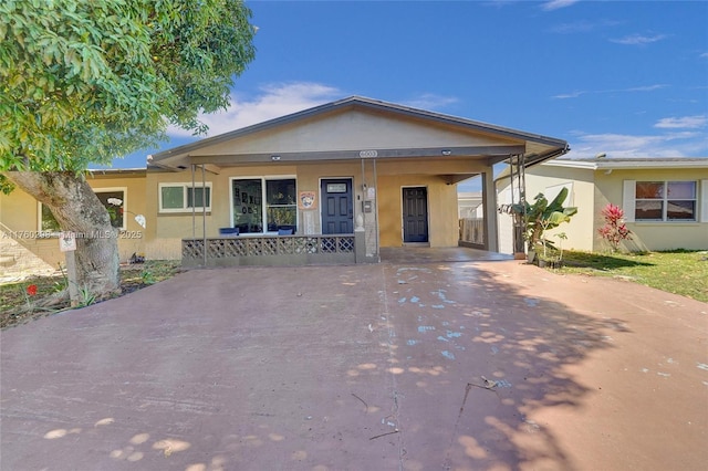 view of front of home featuring covered porch, driveway, and stucco siding