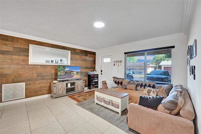 living room with visible vents, ornamental molding, wood walls, light tile patterned floors, and baseboards