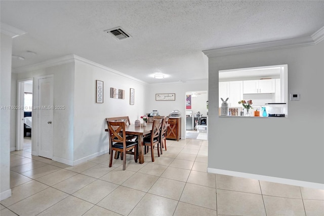 dining space featuring a textured ceiling, light tile patterned floors, visible vents, and ornamental molding