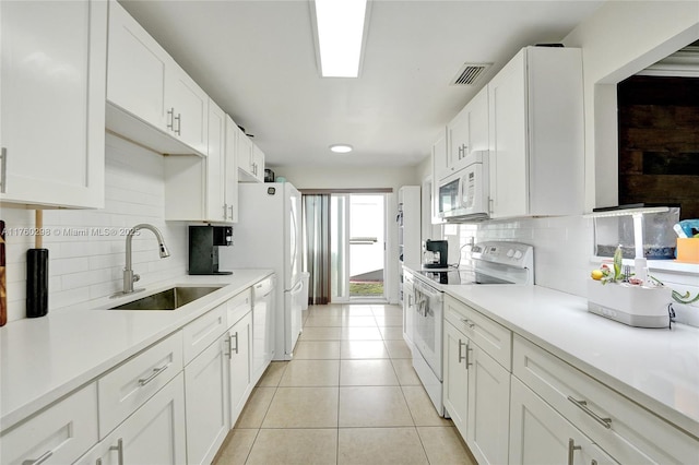 kitchen with white appliances, light tile patterned floors, visible vents, a sink, and white cabinetry