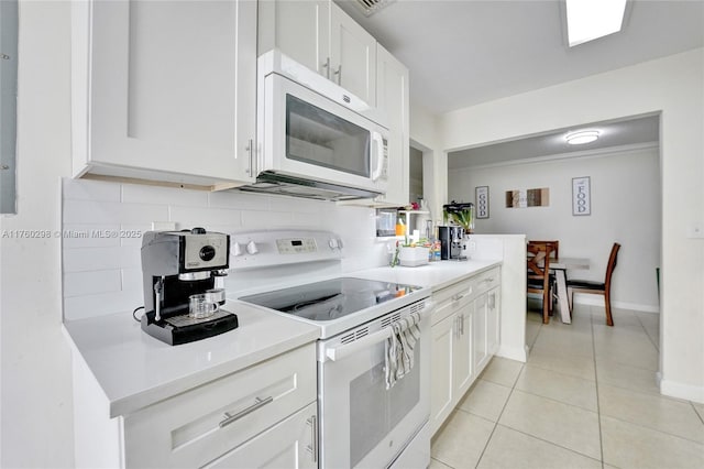 kitchen with white appliances, white cabinets, light countertops, light tile patterned floors, and decorative backsplash