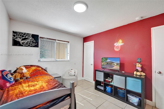 bedroom featuring baseboards, a textured ceiling, and tile patterned flooring