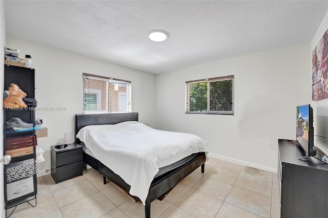 bedroom featuring light tile patterned floors, multiple windows, a textured ceiling, and baseboards