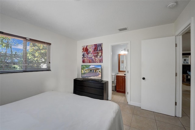 bedroom featuring light tile patterned floors, visible vents, and connected bathroom