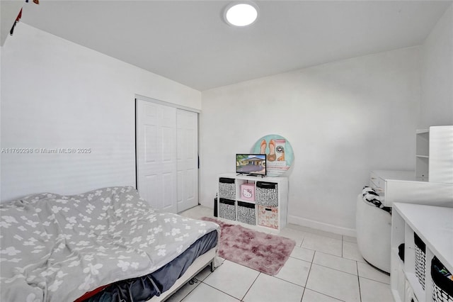 bedroom featuring light tile patterned floors, a closet, and baseboards