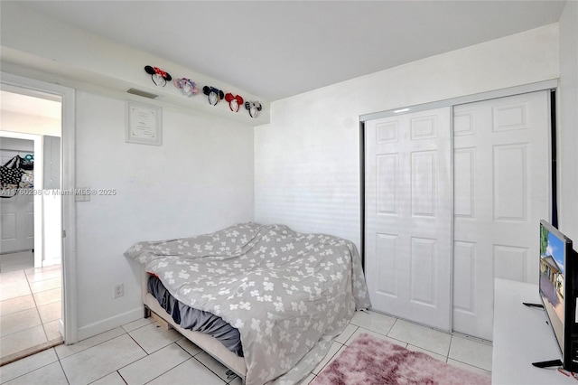 bedroom with tile patterned floors, visible vents, and a closet