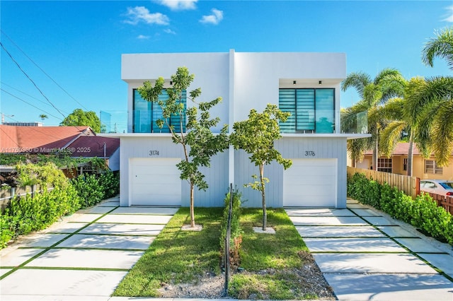 view of front of house featuring driveway, a garage, and fence