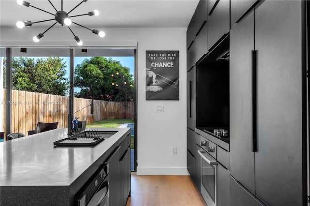 kitchen featuring light wood-type flooring, stainless steel appliances, stainless steel countertops, and a healthy amount of sunlight