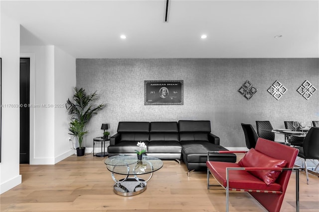 living area featuring recessed lighting, an accent wall, baseboards, and wood finished floors