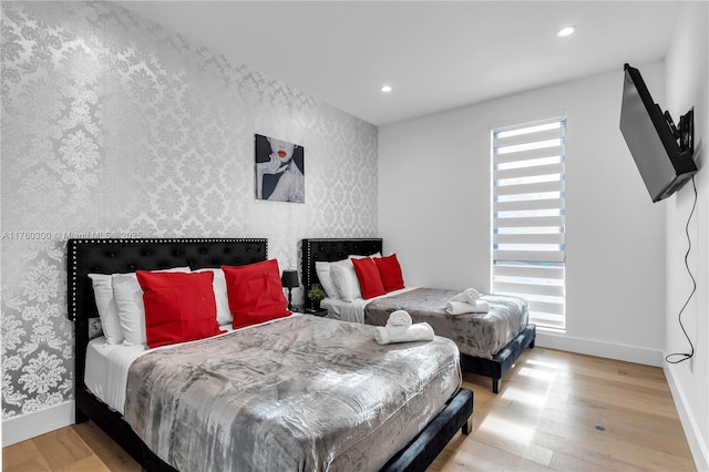 bedroom featuring recessed lighting, wallpapered walls, baseboards, and wood finished floors