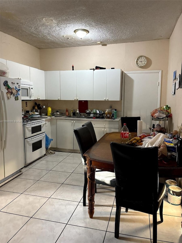 kitchen with light tile patterned floors, white appliances, white cabinetry, and a textured ceiling