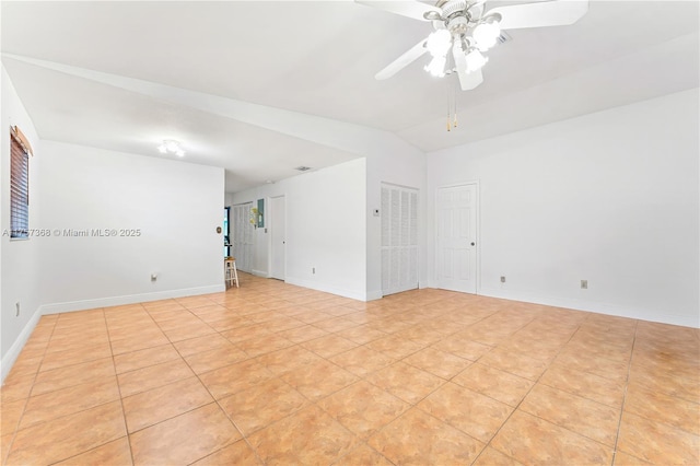 empty room featuring baseboards, lofted ceiling, light tile patterned flooring, and a ceiling fan