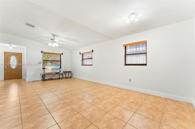 empty room featuring light tile patterned flooring, visible vents, baseboards, and vaulted ceiling