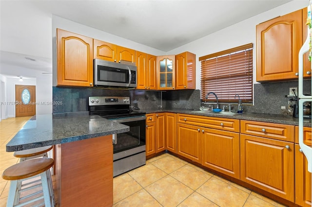 kitchen featuring a sink, backsplash, a kitchen bar, and stainless steel appliances