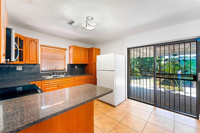 kitchen featuring stainless steel microwave, range with electric cooktop, visible vents, freestanding refrigerator, and a sink