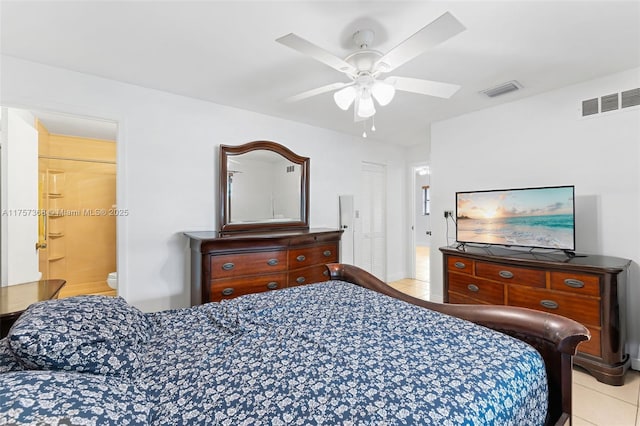 bedroom with light tile patterned floors, visible vents, ensuite bath, and a ceiling fan