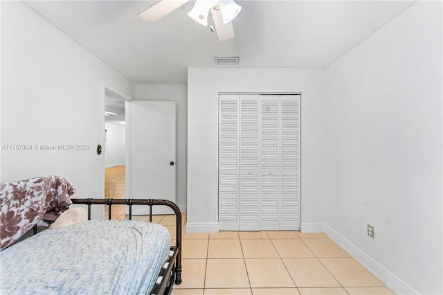 bedroom featuring visible vents, a ceiling fan, a closet, light tile patterned floors, and baseboards