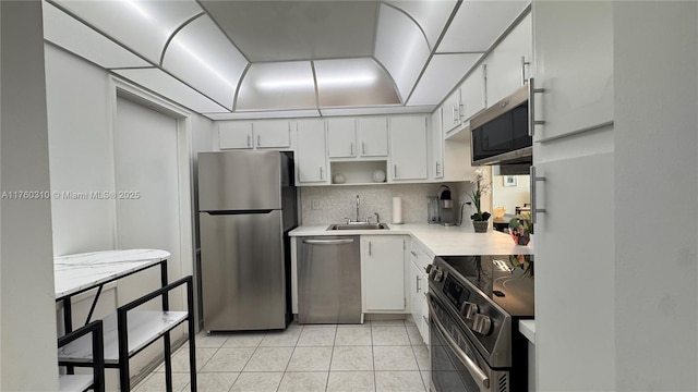 kitchen with a sink, decorative backsplash, light countertops, white cabinets, and stainless steel appliances