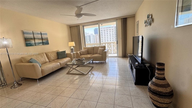 living area featuring ceiling fan, light tile patterned floors, and a textured ceiling