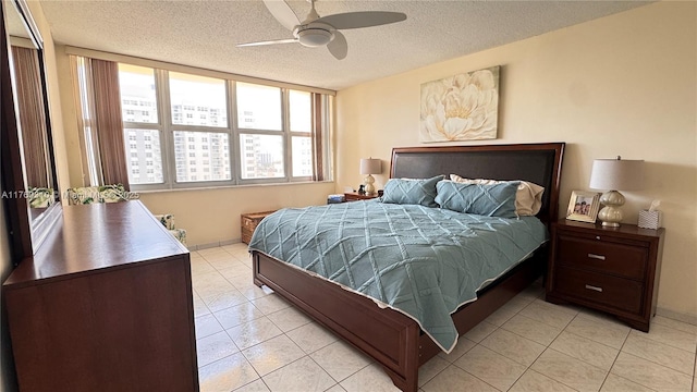 bedroom with a textured ceiling, light tile patterned flooring, and a ceiling fan