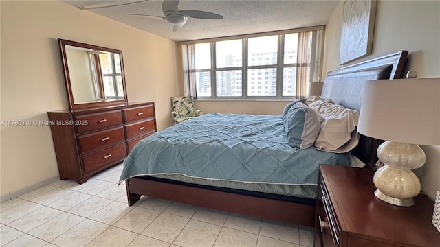 bedroom featuring multiple windows, a ceiling fan, light tile patterned floors, and a textured ceiling