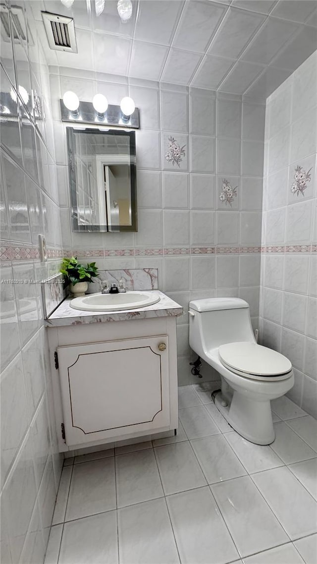 bathroom featuring tile patterned floors, toilet, and tile walls