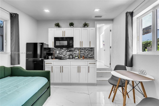 231 NW 44th St, Miami, FL 33127 - kitchen with black appliances, white cabinets, decorative backsplash, and light marble finish floors