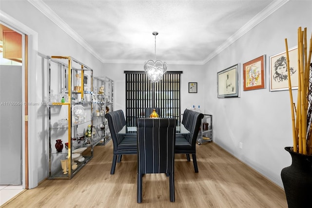 dining room featuring light wood-type flooring, a notable chandelier, and crown molding