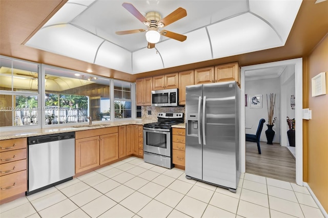 kitchen featuring light tile patterned floors, a sink, ceiling fan, stainless steel appliances, and tasteful backsplash